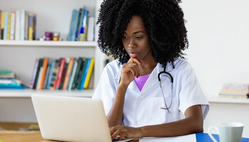 A doctor in a white coat using a computer