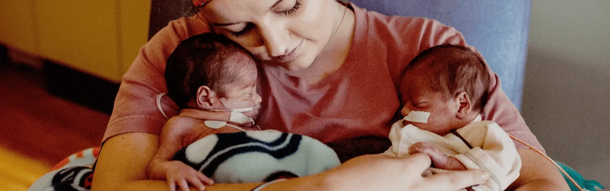 Mother holding two NICU babies.