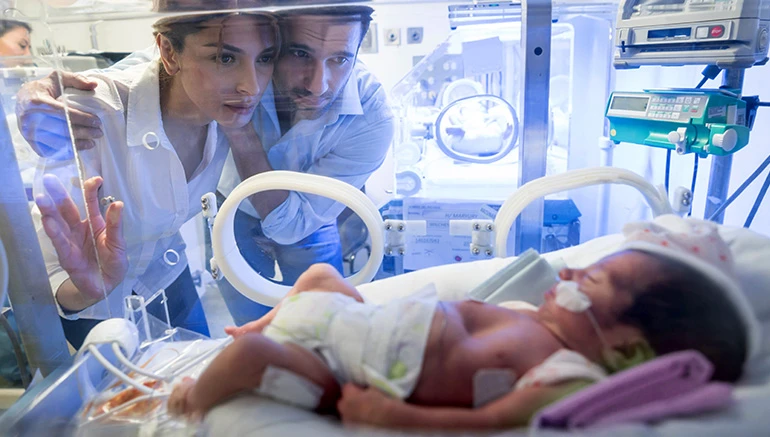 Parents looking at baby in an incubator